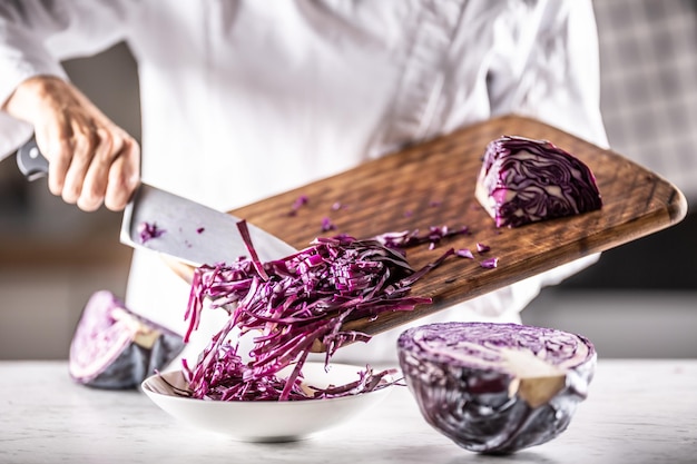 Cavolo rosso tagliato a striscioline messe da un tagliere in una ciotola.