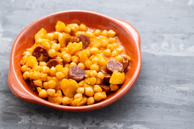 Ceci con patate e salsiccia affumicata su piatto in ceramica