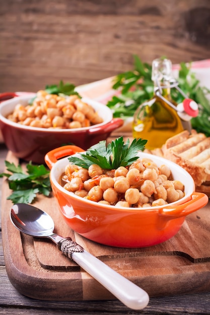 Ceci cotti vegetariani con pomodoro e prezzemolo sulla vecchia superficie di legno. Messa a fuoco selettiva.