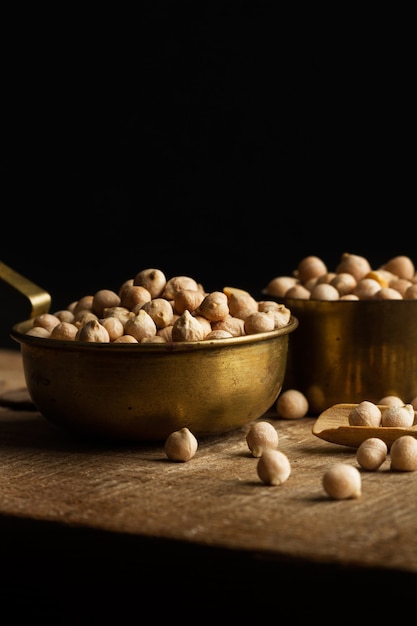 Ceci crudi in cucchiai su una tavola da cucina in legno su sfondo scuro