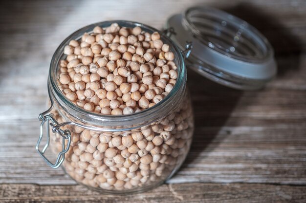 Ceci crudi in un barattolo di vetro su una vecchia tavola di legno. Prodotto vegano sano