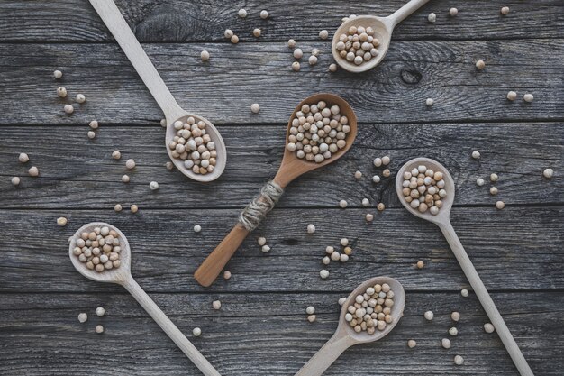 Ceci o ceci secchi crudi in vari tipi di cucchiai sulla tavola di legno vegetaria...