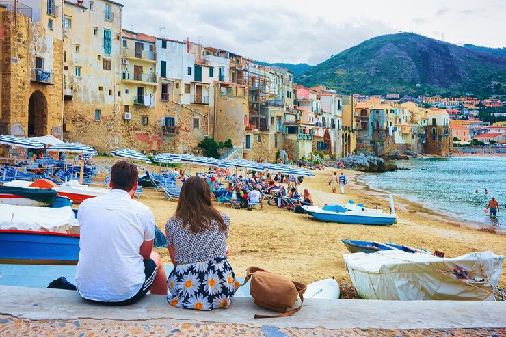 Cefalù, Italia - 26 settembre 2017: Coppia giovane seduto sulla spiaggia nel centro storico di Cefalù, regione Palermo, Sicilia isola in Italia