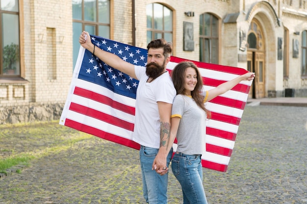 Celebrando insieme il giorno dell'indipendenza Hipster e donna sexy che tiene la bandiera americana il giorno dell'indipendenza Coppia di famiglia felice che commemora l'anniversario dell'indipendenza delle nazioni Felice giorno dell'indipendenza