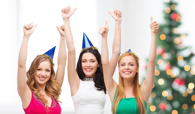 celebrazione, amici, addio al nubilato, concetto di compleanno - tre donne sorridenti che indossano cappelli blu e mostrano i pollici in su