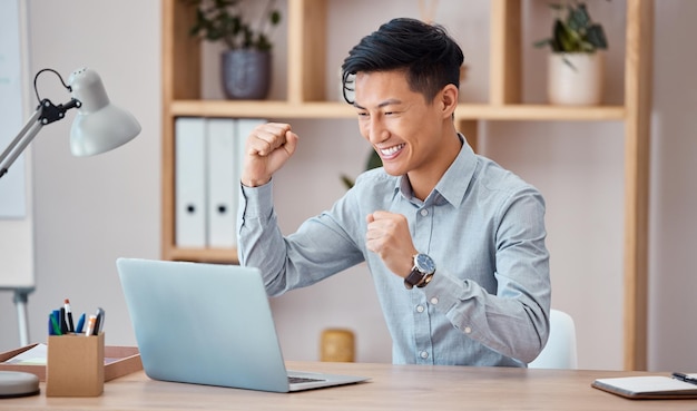 Celebrazione del successo e uomo d'affari che lavora su un laptop con motivazione in un ufficio al lavoro Felice vincita e lavoratore asiatico con un sorriso per celebrare il successo in un'e-mail con un computer