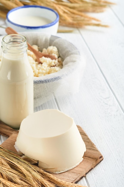 Celebrazione della festa ebraica di Shavuot Latte e formaggio grano maturo e crema di frutta su fondo di legno bianco Prodotti lattiero-caseari su fondo di legno bianco Concetto di Shavuot Vista dall'alto Mock up