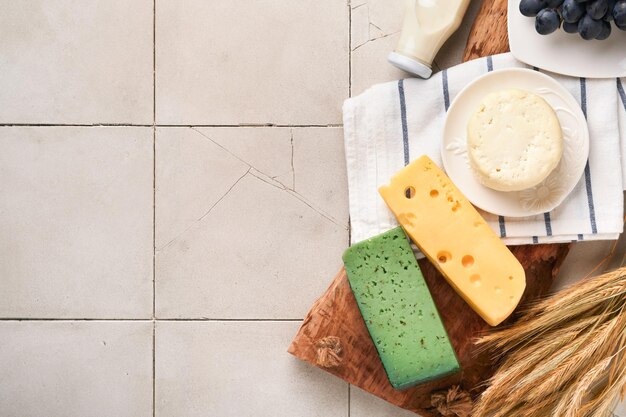 Celebrazione della festa ebraica di Shavuot Latte e formaggio grano maturo e frutta crema vecchio sfondo muro di piastrelle incrinate Prodotti lattiero-caseari su sfondo grigio Concetto di Shavuot Vista dall'alto Mock up