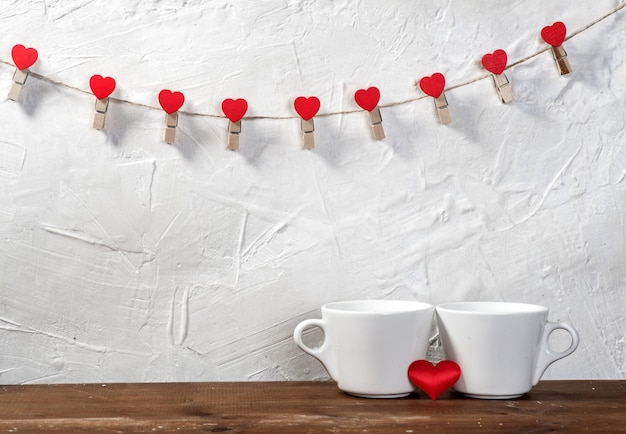 Celebrazione di festa di San Valentino con cuori e tazze sopra il fondo del bokeh