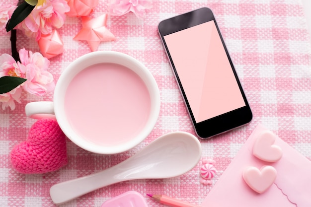 Celebrazione di festa di San Valentino con tazza di latte e smartphone schermo vuoto.