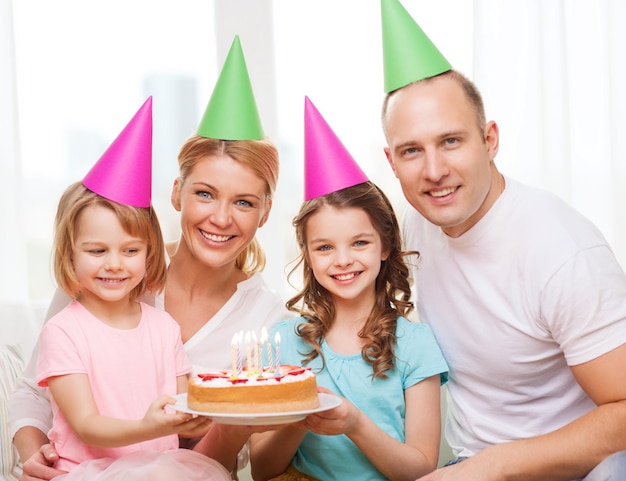 celebrazione, famiglia, vacanze e concetto di compleanno - famiglia felice con due bambini in cappelli con torta a casa