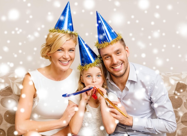 celebrazione, famiglia, vacanze e concetto di compleanno - tre donne sorridenti che indossano cappelli blu e soffiano corna di favore