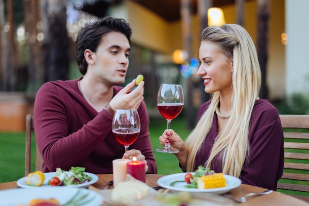Celebrazione romantica. Felice coppia positiva seduti insieme nel ristorante bevendo vino