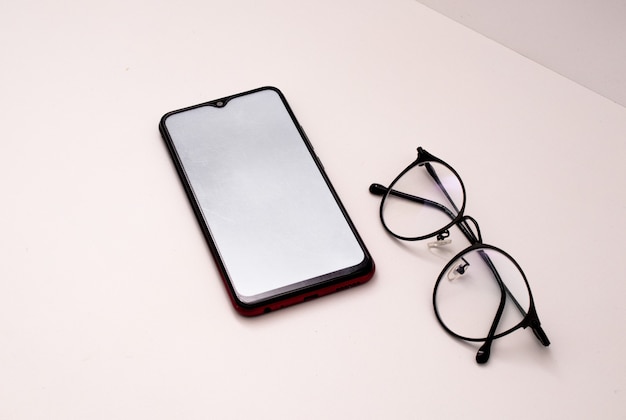 cellulare e occhiali su sfondo bianco