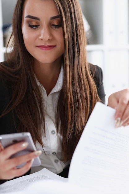 Cellulare sorridente di conversazione della donna di affari della bella brunetta in ritratto dell'ufficio.