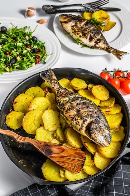 Cena con pesce orata alla griglia insalata di rucola con pomodori patate al forno