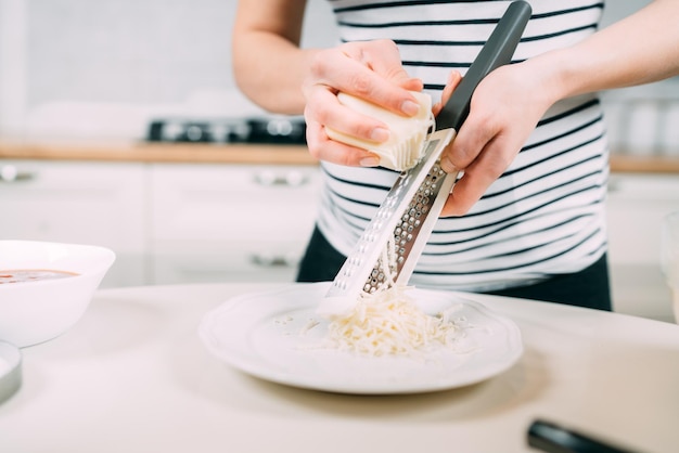 Cena fatta in casa con felice donna incinta che cucina pizza con formaggio e mozzarella