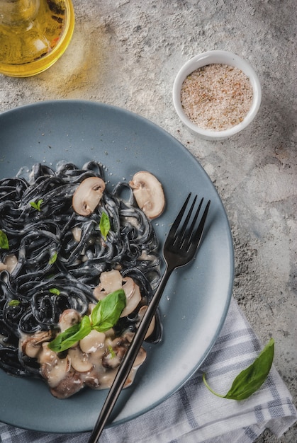 Cena moderna italiana Spaghetti al nero di seppia con spaghetti all'olio d'oliva e basilico