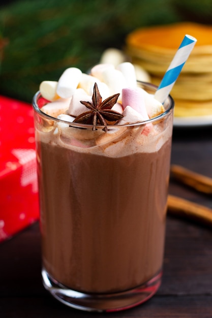 Cena romantica. Un bicchiere di cioccolata calda e un regalo rosso sullo sfondo.