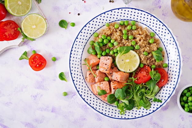 Cena salutare. Fette di salmone grigliato, quinoa, piselli, pomodoro, foglie di lime e lattuga. Disteso.