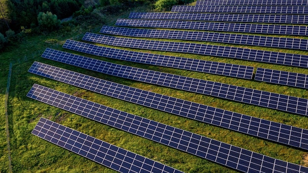 Centrale elettrica solare nel campo verde il giorno soleggiato. Vista aerea. Supporti per pannelli solari