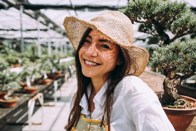 Centro serra bonsai. file con piccoli alberi, donna che lavora e si prende cura delle piante