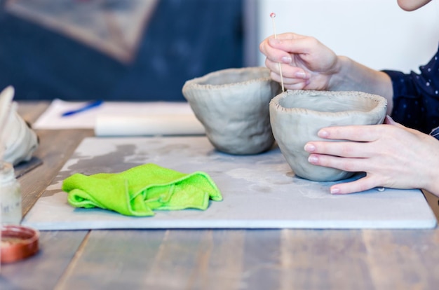 Ceramica Uno scultore fa un piatto da un vasaio di argilla che lavora con il primo piano delle mani di pennello di argilla applica un motivo al prodotto
