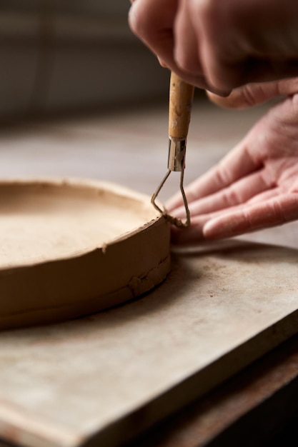 Ceramista femminile che lavora nello studio della ceramica. Le mani del ceramista sporche di argilla. Processo di creazione della ceramica. Il maestro ceramista lavora nel suo studio