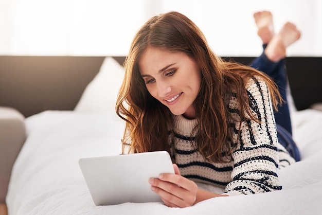 Cerca felice e tablet con donna a letto per la comunicazione sui social media e la tecnologia Internet digitale e il sito Web con una persona di sesso femminile che legge online a casa per lo streaming di ebook e la felicità