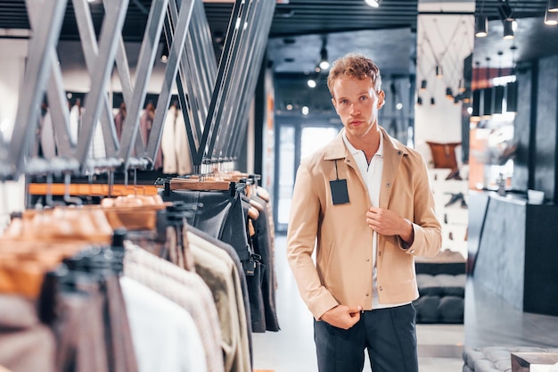 Cerca giacca Ragazzo giovane in un negozio moderno con vestiti nuovi Abbigliamento elegante e costoso per gli uomini