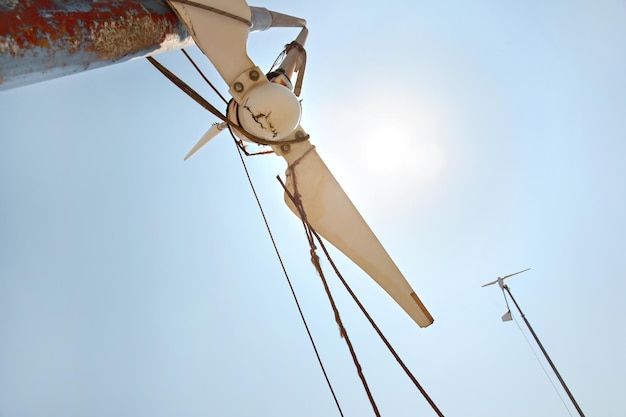 Cercando una piccola turbina eolica rotta, un forte sole di mezzogiorno che splende nel cielo.