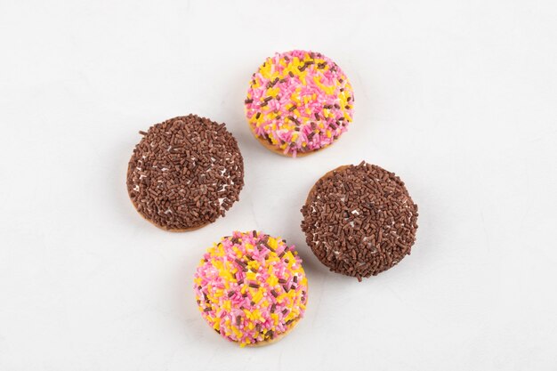 Cerchio di biscotti freschi con granelli colorati posizionati sulla superficie bianca.