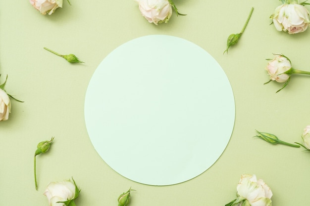 Cerchio di carta bianca su sfondo verde. Decorazioni floreali.