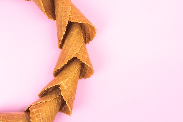 Cerchio liscio di coni di cialda per gelato su sfondo rosa.