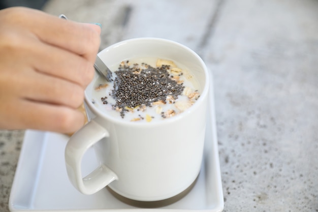 Cereale sul latte in tazza con la prima colazione della mano della donna