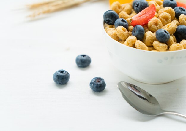 Cereali con mirtilli, latte e miele colazione su uno sfondo bianco