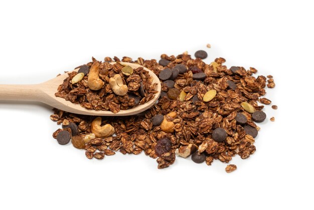 Cereali di muesli al cioccolato con noci in un cucchiaio di legno. Isolato su bianco