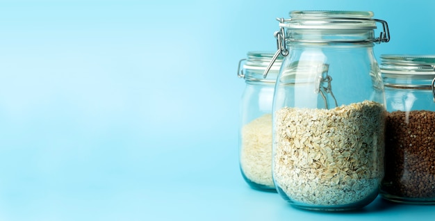 Cereali (farina d'avena, grano saraceno, riso) in barattoli di vetro in cucina. Concetto senza glutine. Varietà di cereali per preparare cibi e pasti sani e fatti in casa.