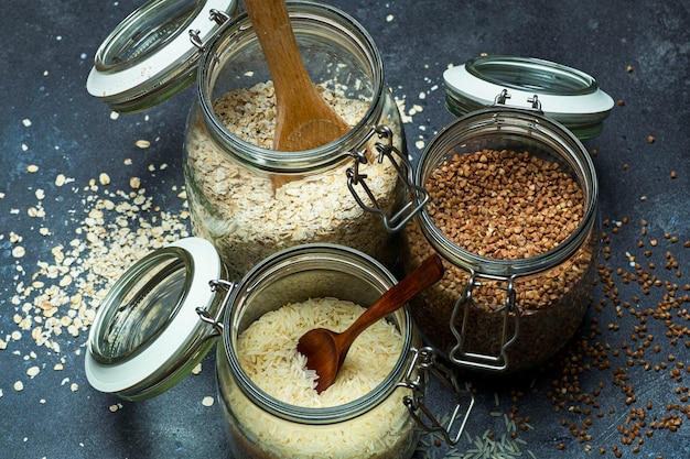 Cereali (farina d'avena, grano saraceno, riso) in barattoli di vetro in cucina. Concetto senza glutine. Varietà di cereali per preparare cibi e pasti sani e fatti in casa.