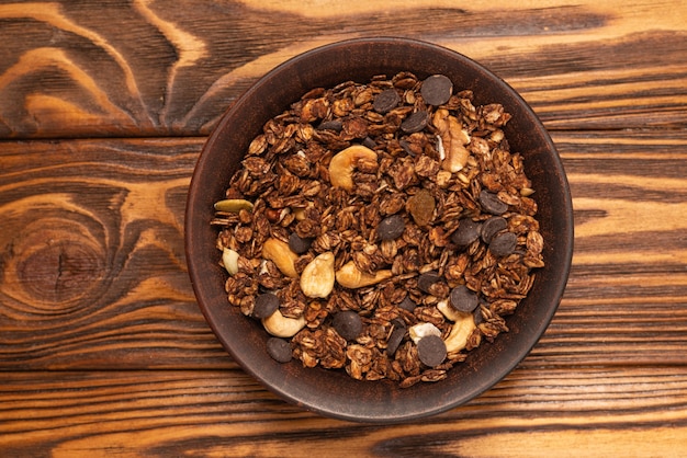 Cereali muesli al cioccolato con noci in una ciotola su legno