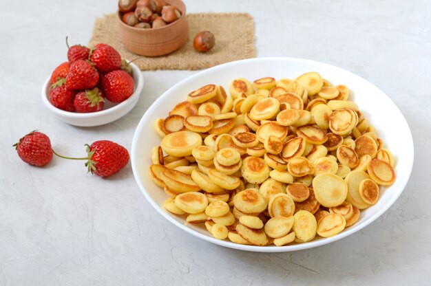 Cereali per frittelle in una ciotola con fragole fresche e noci su una superficie leggera