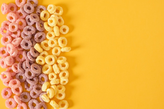 Cereali per la colazione colorati su sfondo giallo vista dall'alto
