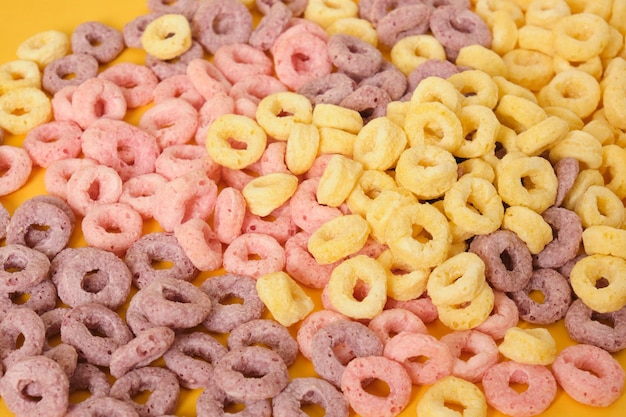 Cereali per la colazione colorati su sfondo giallo vista dall'alto