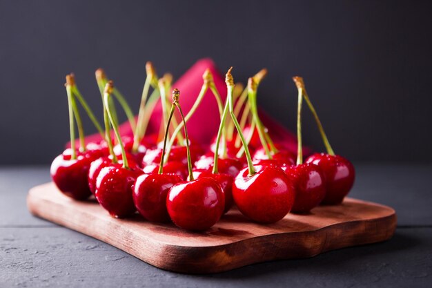 Cereie su sfondo scuro Cereie rosse su tavola di legno Bacche in gocce d'acqua su tovagliolo rosso