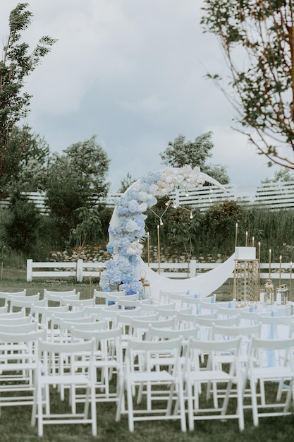 cerimonia di matrimonio all'aperto allestita con sedie bianche e fiori bohémien