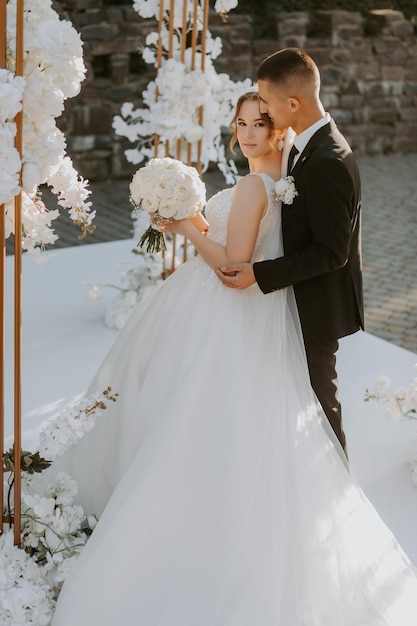 Cerimonia matrimoniale. Felice sposa, sposo e damigelle d'onore vicino al bellissimo arco di nozze