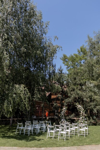 Cerimonia nuziale all'aperto con uno splendido arco floreale e sedie bianche disposte in un giardino sereno