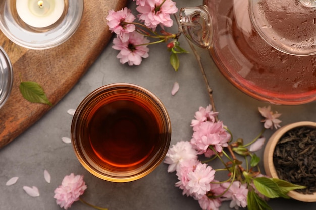 Cerimonia tradizionale Coppa di tè preparata e fiori di sakura su un tavolo grigio