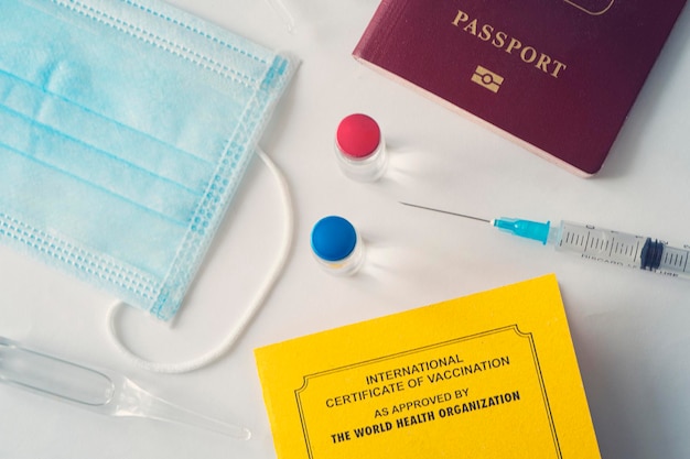 Certificato internazionale di vaccinazione un documento per la registrazione dei vaccini effettuati. il documento è di colore giallo. passaporto di un cittadino straniero e una siringa sul tavolo. concetto di viaggio sicuro.
