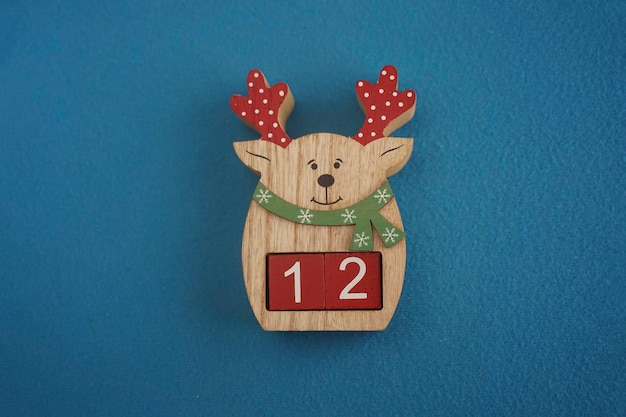 Cervo di legno festivo con Viva Magenta cubi 12 su sfondo blu close-up vista superiore concetto natalizio di data o ora numeri divertenti 12 su cubi rossi copiare spazio per testo o evento cubi educativi